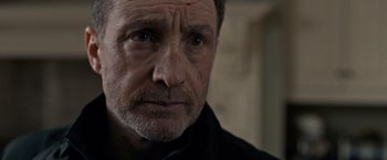 Movie still from “The Foreigner” (2017), directed by Martin Campbell – A person wearing a black shirt; Close Up shot, Over the shoulder angle