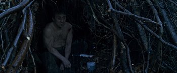 Movie still from “The Foreigner” (2017), directed by Martin Campbell – A man sitting in the woods next to a tree; Medium shot, High angle