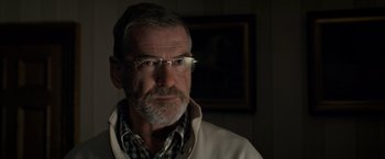 Movie still from “The Foreigner” (2017), directed by Martin Campbell – An older man wearing glasses in a room with a painting on the wall behind him; Close Up shot, Over the shoulder angle