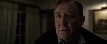 Movie still from “The Foreigner” (2017), directed by Martin Campbell – An older man wearing a black jacket looking at the camera; Close Up shot, Over the shoulder angle