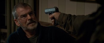 Movie still from “The Foreigner” (2017), directed by Martin Campbell – An older man holding a gun in front of him; Close Up shot, Over the shoulder angle