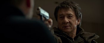 Movie still from “The Foreigner” (2017), directed by Martin Campbell – A man holding a gun in front of another man; Close Up shot, Over the shoulder angle