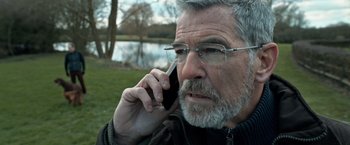 Movie still from “The Foreigner” (2017), directed by Martin Campbell – An older man talking on a cell phone outside; Close Up shot, Low angle
