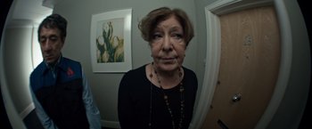 Movie still from “The Foreigner” (2017), directed by Martin Campbell – An older woman is standing in front of a mirror; Close Up shot, High angle