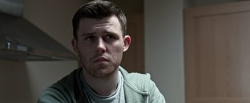 Movie still from “The Foreigner” (2017), directed by Martin Campbell – A person wearing a jacket looking at the camera; Close Up shot, Over the shoulder angle