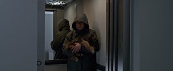 Movie still from “The Foreigner” (2017), directed by Martin Campbell – A person holding a dog in a room; Medium shot, High angle