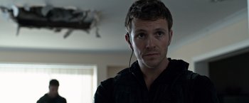 Movie still from “The Foreigner” (2017), directed by Martin Campbell – A person wearing headphones; Close Up shot, Over the shoulder angle