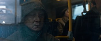 Movie still from “The Foreigner” (2017), directed by Martin Campbell – A man in a hooded jacket riding on a bus; Close Up shot, Low angle