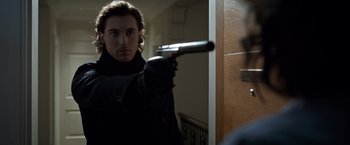 Movie still from “The Foreigner” (2017), directed by Martin Campbell – A man holding a gun in front of a door; Close Up shot, Over the shoulder angle