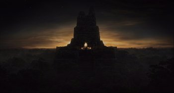 Movie still from “The Fountain” (2006), directed by Darren Aronofsky – A large stone structure with a fire in the middle of it at night; Extreme Wide shot, Low angle