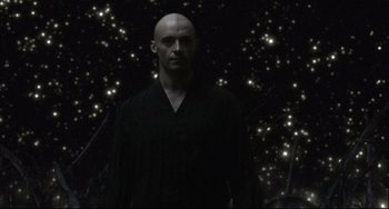 Movie still from “The Fountain” (2006), directed by Darren Aronofsky – A bald man in a black shirt is standing in front of some lights; Medium shot, Low angle