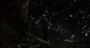 Movie still from “The Fountain” (2006), directed by Darren Aronofsky – A man standing in front of a tree in the dark; Wide shot, Low angle