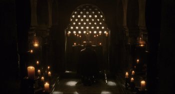 Movie still from “The Fountain” (2006), directed by Darren Aronofsky – A person sitting in a dark room with candles; Extreme Wide shot, High angle