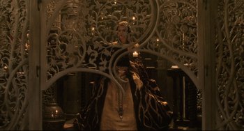 Movie still from “The Fountain” (2006), directed by Darren Aronofsky – A woman is sitting in front of a wall with candles; Wide shot, High angle