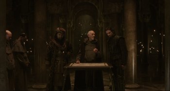 Movie still from “The Fountain” (2006), directed by Darren Aronofsky – A group of men standing around a table; Wide shot, Low angle