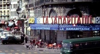 Movie still from “The French Connection” (1971), directed by William Friedkin – A group of people sitting at tables outside of a restaurant; Extreme Wide shot, High angle