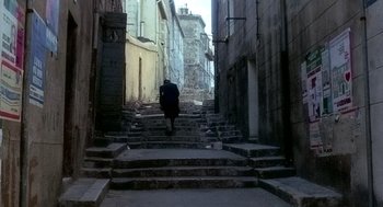 Movie still from “The French Connection” (1971), directed by William Friedkin – A person walking down a set of stairs in an alleyway; Wide shot, High angle