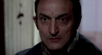 Movie still from “The French Connection” (1971), directed by William Friedkin – A person's face in a dark room; Close Up shot, Low angle