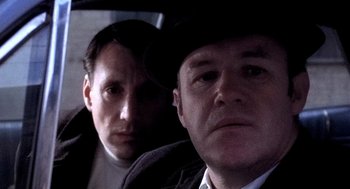 Movie still from “The French Connection” (1971), directed by William Friedkin – Two men are sitting in the back of a car; Close Up shot, Low angle