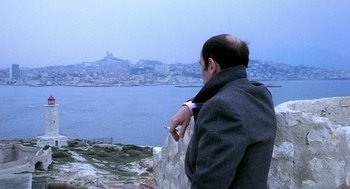 Movie still from “The French Connection” (1971), directed by William Friedkin – A man looking out over the water from a cliff; Medium shot, High angle
