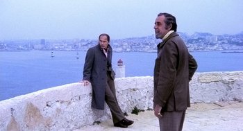 Movie still from “The French Connection” (1971), directed by William Friedkin – A couple of men standing next to each other on top of a wall; Wide shot, High angle