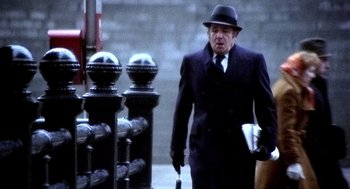 Movie still from “The French Connection” (1971), directed by William Friedkin – An older man in a suit and hat walking down the street; Medium shot, Low angle