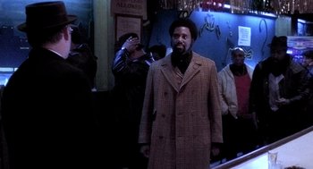 Movie still from “The French Connection” (1971), directed by William Friedkin – A man standing in front of a group of people; Medium shot, Low angle