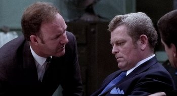 Movie still from “The French Connection” (1971), directed by William Friedkin – Two men in business suits talking to each other; Close Up shot, Over the shoulder angle