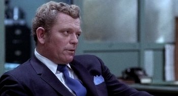 Movie still from “The French Connection” (1971), directed by William Friedkin – An older man wearing a suit and tie; Close Up shot, Over the shoulder angle