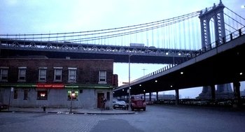 Movie still from “The French Connection” (1971), directed by William Friedkin – A red van parked on the side of the road under a bridge; Extreme Wide shot, Low angle