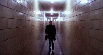 Movie still from “The French Connection” (1971), directed by William Friedkin – A man walking down a long hallway in a building; Wide shot, Low angle