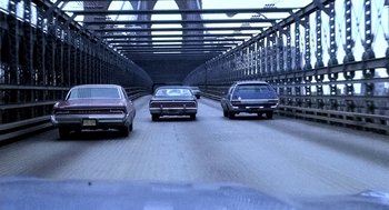 Movie still from “The French Connection” (1971), directed by William Friedkin – A group of cars driving down a bridge; Wide shot, High angle