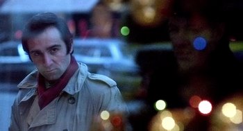Movie still from “The French Connection” (1971), directed by William Friedkin – A man standing in front of a street light; Close Up shot, Over the shoulder angle