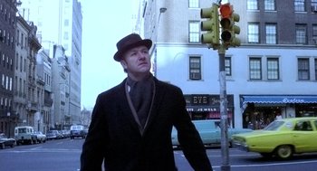 Movie still from “The French Connection” (1971), directed by William Friedkin – A man wearing a hat and a suit walking down the street; Medium shot, Low angle