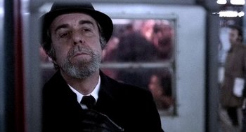 Movie still from “The French Connection” (1971), directed by William Friedkin – An older man wearing a hat and a tie; Close Up shot, Low angle