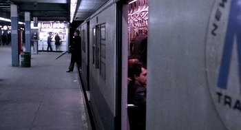 Movie still from “The French Connection” (1971), directed by William Friedkin – A man sitting on a subway train next to a person standing; Wide shot, High angle