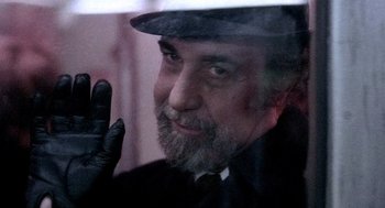 Movie still from “The French Connection” (1971), directed by William Friedkin – An older man wearing a hat and gloves; Close Up shot, Over the shoulder angle