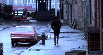 Movie still from “The French Connection” (1971), directed by William Friedkin – A man walking down a street next to a fire hydrant; Wide shot, Over the shoulder angle