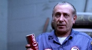 Movie still from “The French Connection” (1971), directed by William Friedkin – An older man is holding a can of coke; Close Up shot, High angle