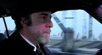 Movie still from “The French Connection” (1971), directed by William Friedkin – A man wearing a suit and a hat looking out a car window; Close Up shot, Over the shoulder angle
