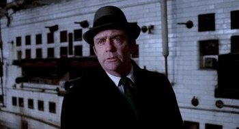 Movie still from “The French Connection” (1971), directed by William Friedkin – A man wearing a hat and a suit and tie; Close Up shot, Low angle