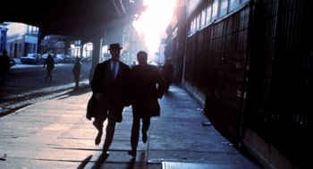 Movie still from “The French Connection” (1971), directed by William Friedkin – Two people walking down a street in a city; Wide shot, High angle