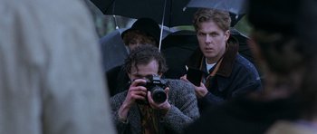 Movie still from “The Frighteners” (1996), directed by Peter Jackson – A man taking a picture of a group of people under an umbrella; Close Up shot, Over the shoulder angle