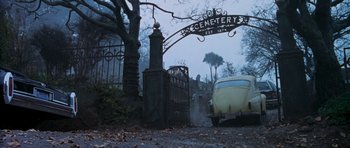 Movie still from “The Frighteners” (1996), directed by Peter Jackson – A car parked in front of a cemetery sign; Wide shot, Low angle
