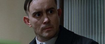 Movie still from “The Frighteners” (1996), directed by Peter Jackson – A person wearing a suit and tie; Close Up shot, Over the shoulder angle