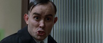 Movie still from “The Frighteners” (1996), directed by Peter Jackson – A person wearing a suit and tie; Close Up shot, Low angle