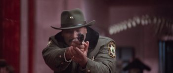 Movie still from “The Frighteners” (1996), directed by Peter Jackson – A man in a uniform holding a gun in his hands; Close Up shot, Low angle