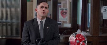 Movie still from “The Frighteners” (1996), directed by Peter Jackson – A man in a suit and tie standing in front of a fan; Close Up shot, Low angle
