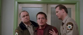Movie still from “The Frighteners” (1996), directed by Peter Jackson – A group of men standing next to each other in a room; Medium shot, Over the shoulder angle