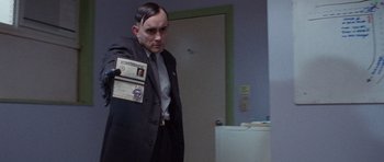 Movie still from “The Frighteners” (1996), directed by Peter Jackson – A man in a suit and tie holding a passport; Medium shot, Over the shoulder angle